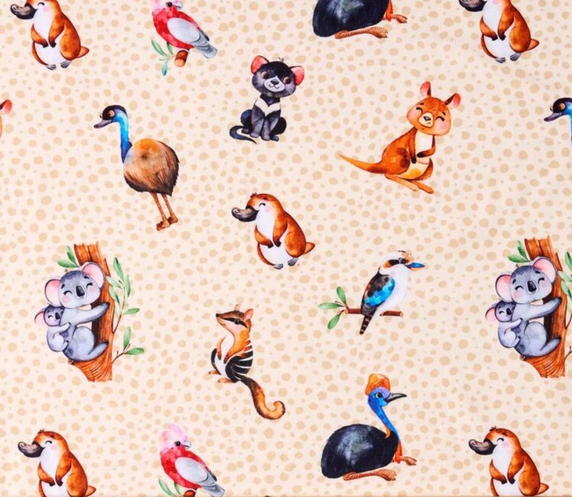 Photo of fabric print showing a pale brown background with cartoon characters depicting koalas, platapus, tasmanian devils, emus, kookaburras, numbats and galashs.