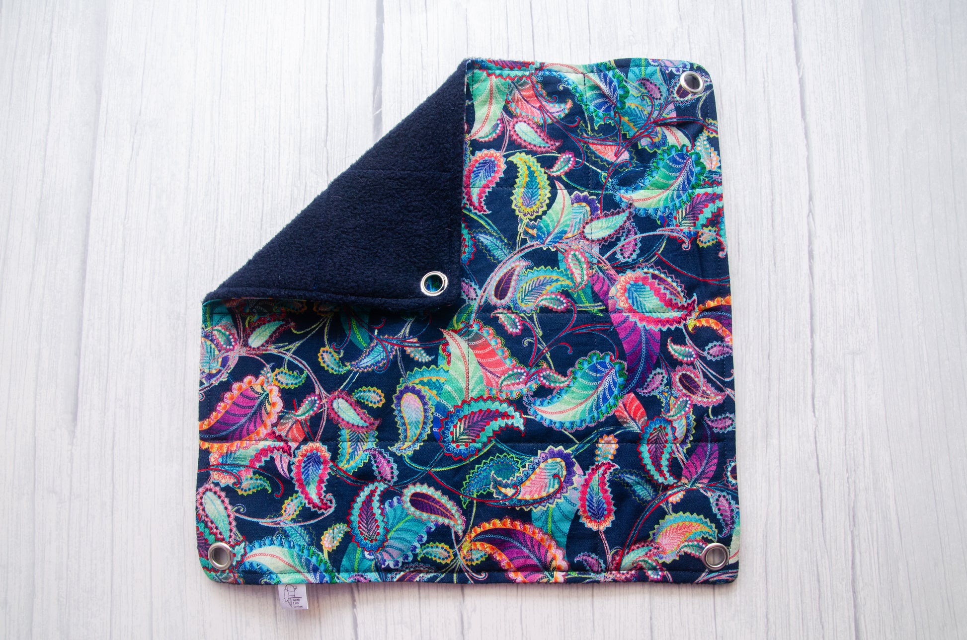 Flat rat hammock laid flat on surface, navy paisley pattern on fabric with 10mm eyelets in each corner