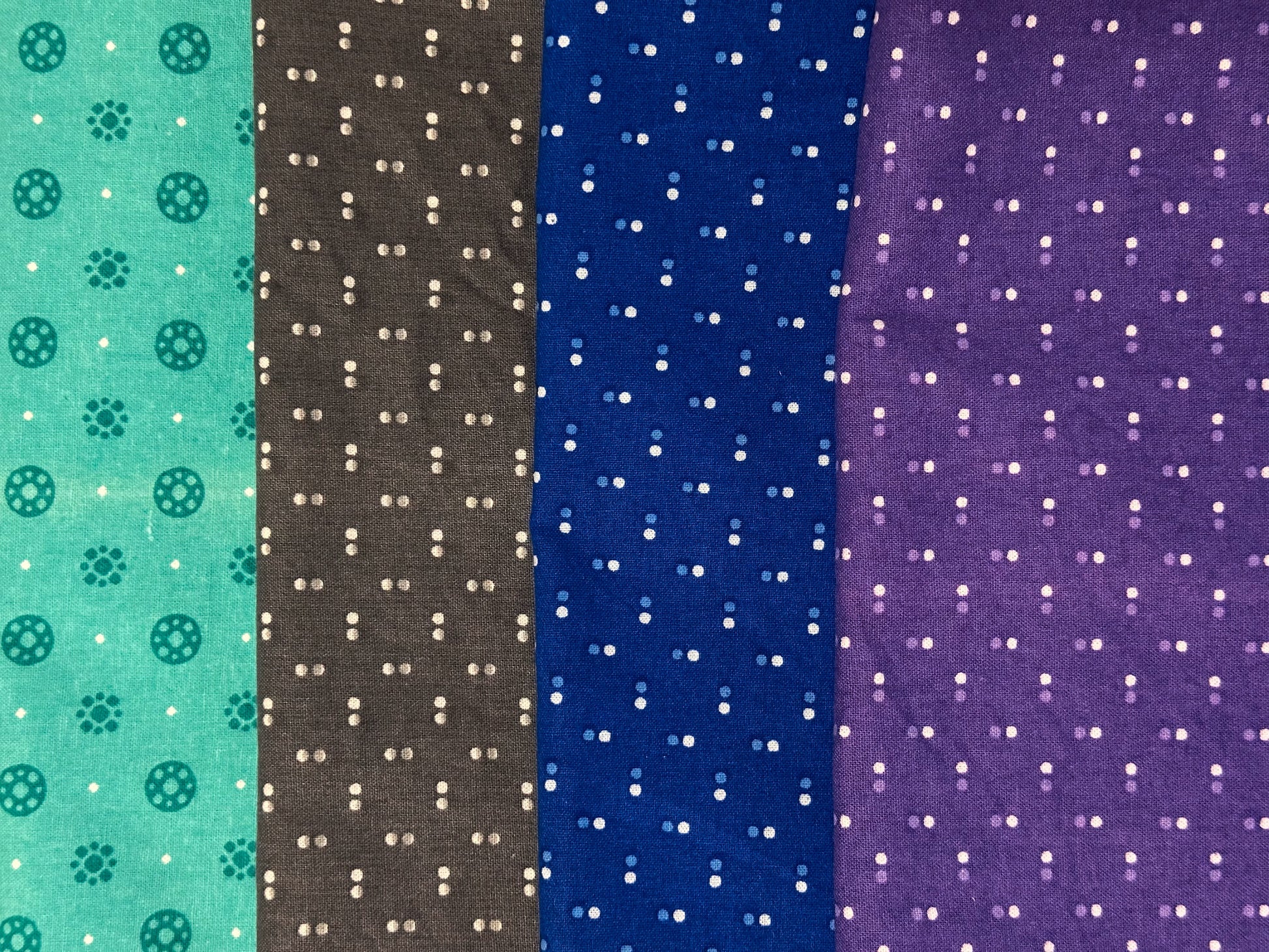 flat lay image of fabrics with dots, top aqua, next grey, next blue and bottom purple